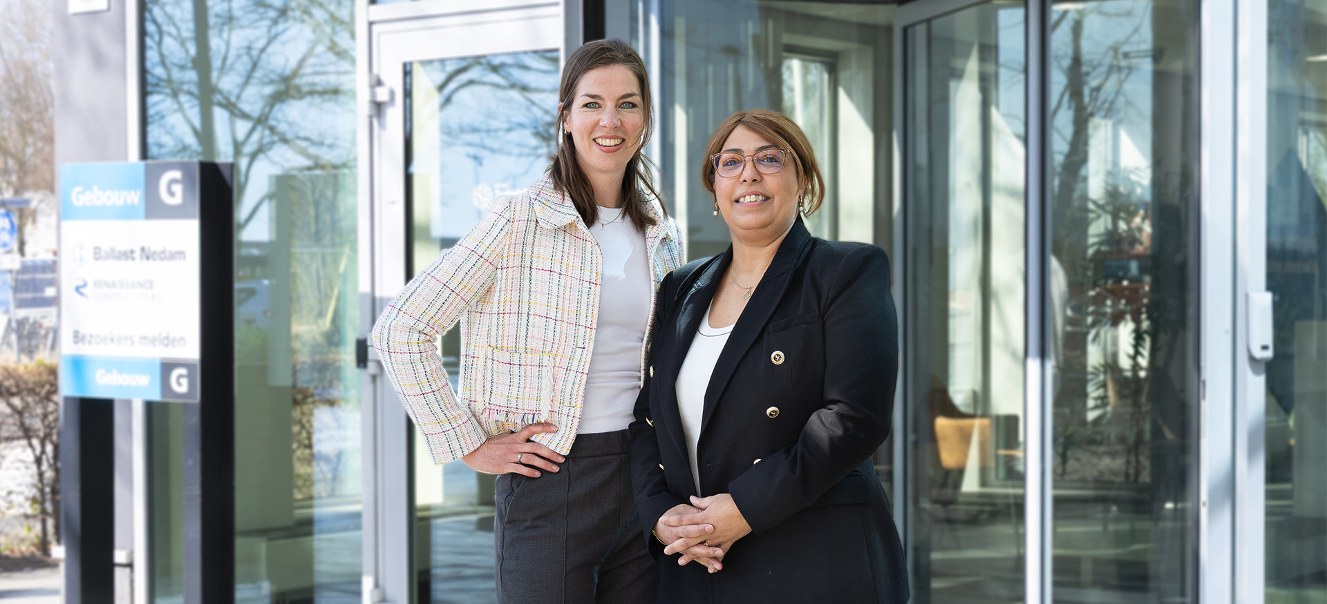 Kamar Larouz en Lisa de Ligt Executiv Assistant bij Ballast Nedam staan voor de ingang van het hoofdkantoor