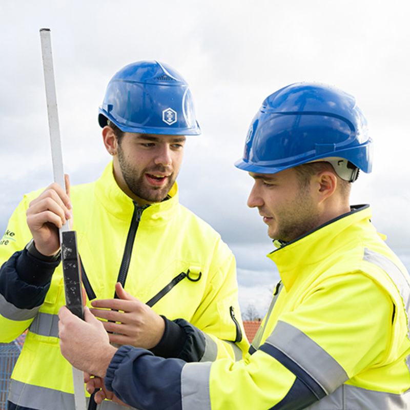 Een medewerker van Ballast Nedam helpt een collega, illustrerend de vele groeimogelijkheden en professionele ontwikkeling binnen Ballast Nedam
